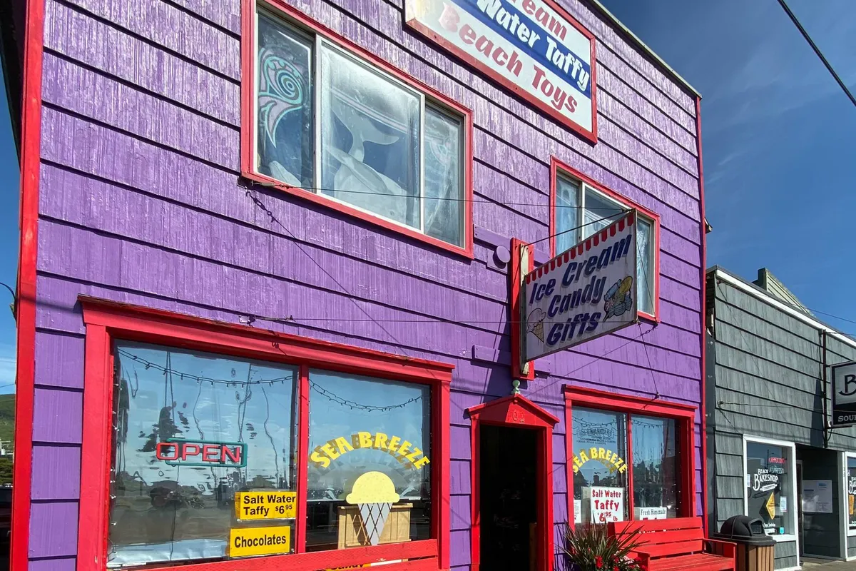 This image captures a vibrant, bright purple exterior of a local shop, featuring an eye-catching ice cream sign and colorful window displays. The playful scene suggests summer fun and beachside treats, hinting at the lively local life just steps from the home.