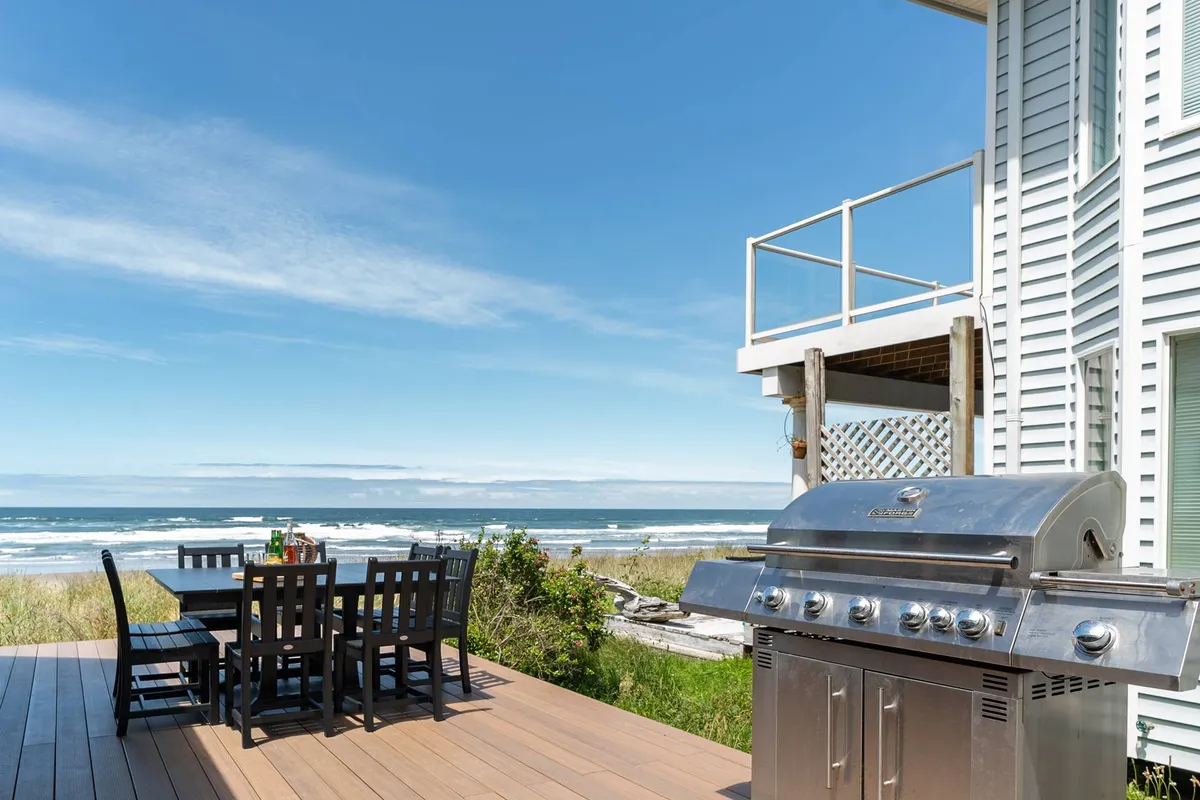 A spacious outdoor deck overlooks sweeping ocean views, with a dining table and grill positioned perfectly for al fresco meals. The relaxed setting is enhanced by gentle ocean breezes and a sense of privacy ideal for group gatherings or evening toasts as the sun sets.