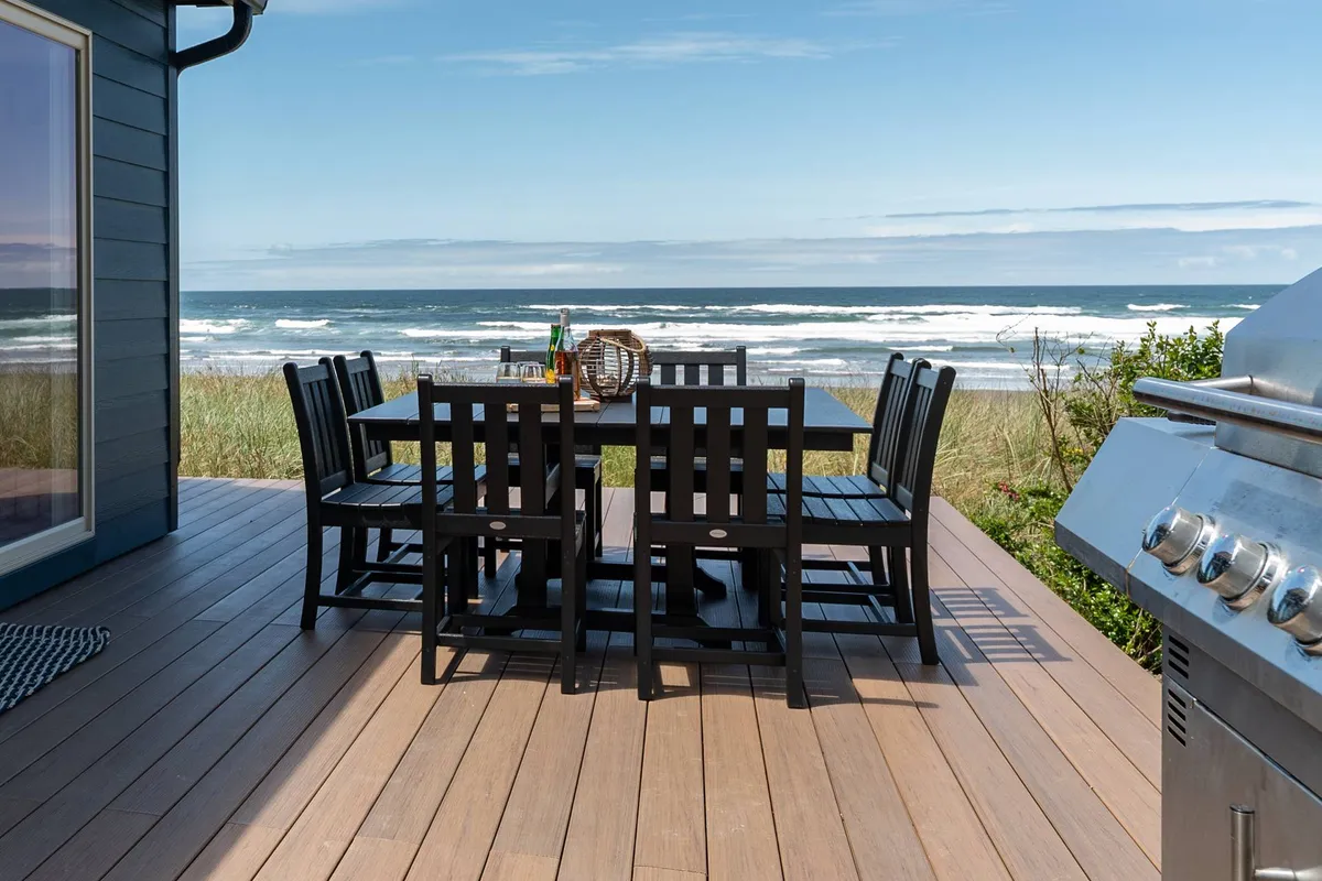 A stylish outdoor dining area with a grill offers a spectacular ocean view. The scene captures a relaxed mood, ideal for social gatherings, barbecues, or simply enjoying the scenery with friends in a luxurious setting.